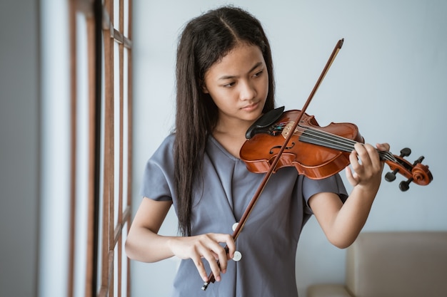 Foto de uma adolescente aprendendo a tocar violino