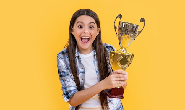 Foto de uma adolescente campeã feliz com uma campeã adolescente de copa dourada isolada em amarelo