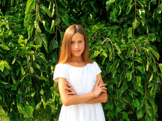 Foto de uma adolescente em pé perto de uma árvore no verão