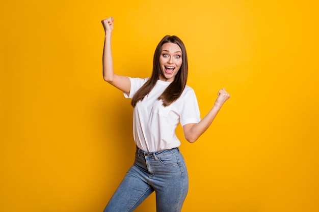 Foto de uma alegre garota dançando isolada em um fundo amarelo brilhante