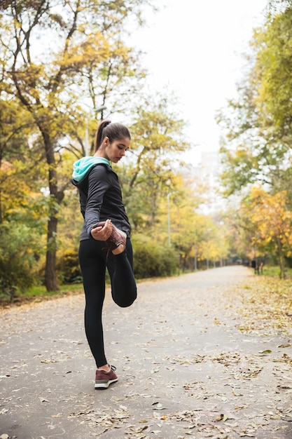 Foto de uma bela jovem bonita fitness ao ar livre no parque fazer exercícios de esporte.