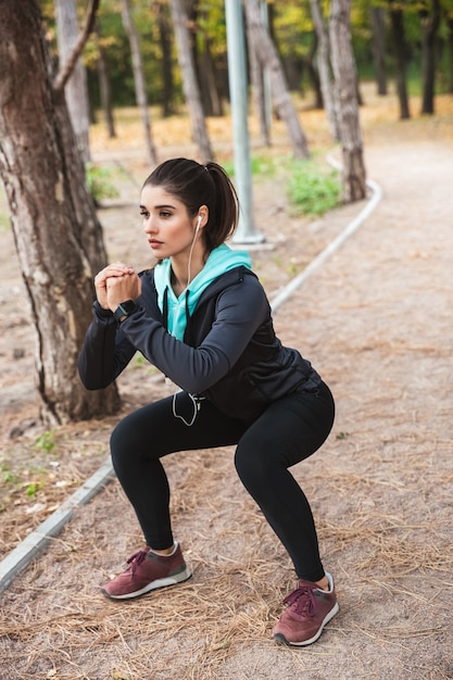 Foto de uma bela jovem bonita fitness ao ar livre no parque fazer exercícios de esporte.