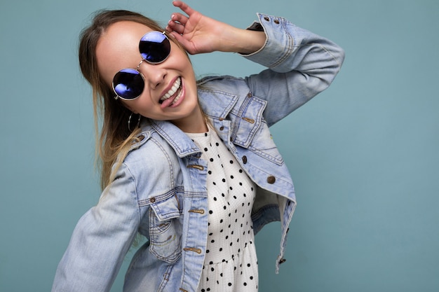 Foto de uma bela jovem loira positiva vestindo roupas casuais de verão e óculos escuros elegantes