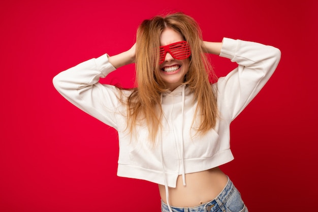 Foto de uma bela jovem loira positiva vestindo roupas casuais e óticas elegantes