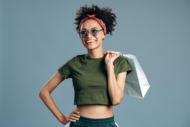 Foto de uma bela modelo multirracial milenar carregando pacotes de compras e segurando-o na frente da câmera