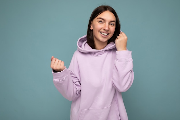 Foto de uma bela mulher adulta sorridente e positiva vestindo roupas elegantes, isolada em um fundo colorido com espaço de cópia, olhando para a câmera