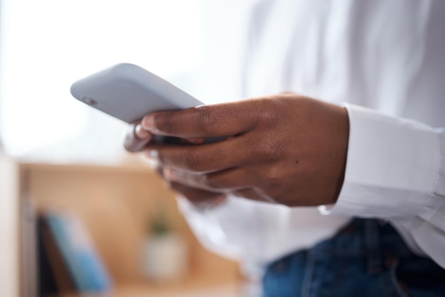 Foto de uma empresária irreconhecível usando um smartphone em um escritório moderno