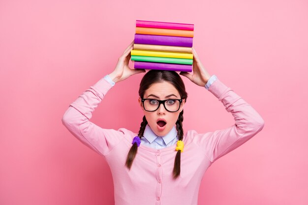 Foto de uma estudante bonita segurando pilha de literatura na cabeça preparando o exame faculdade universidade grande dever de casa oprimido usar camisa pulôver especificações isoladas cor de fundo