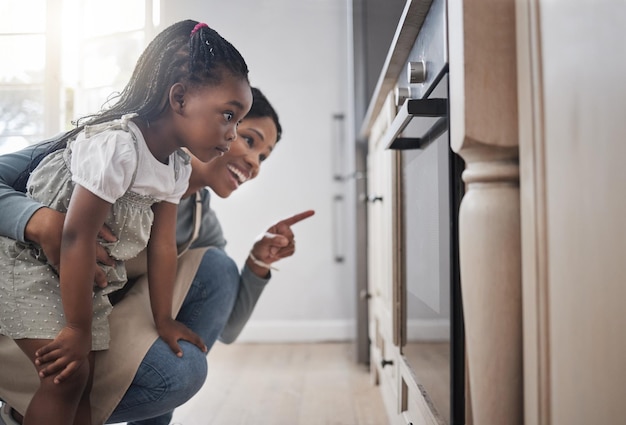 Foto de uma garotinha e sua mãe sentada em frente ao forno