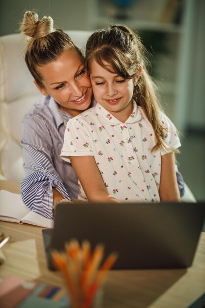 Foto de uma garotinha fofa e sua linda jovem mãe usando laptop em uma videochamada durante a pandemia de COVID-19.