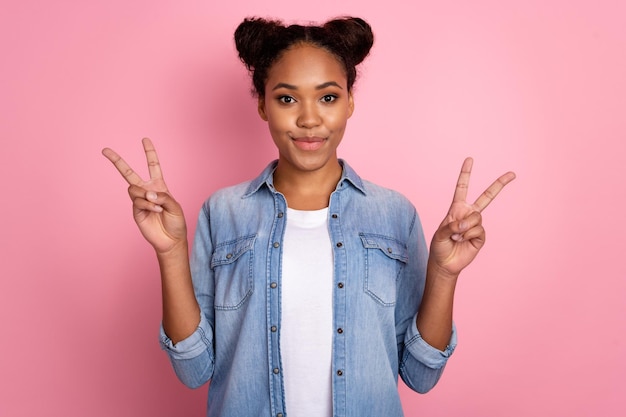 Foto de uma jovem africana mostra os dedos paz legal férias de viagem vsymbol isoladas sobre fundo de cor rosa