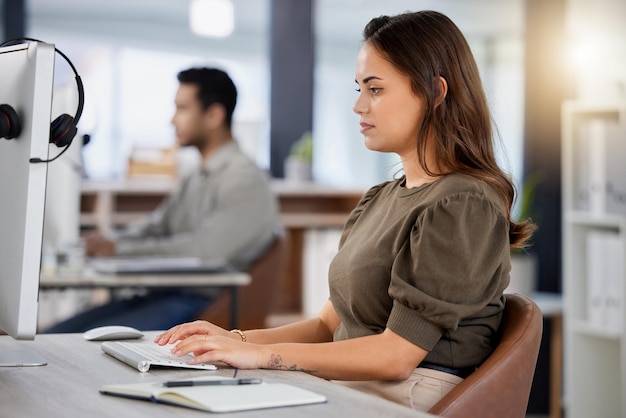 Foto de uma jovem agente de call center feminina usando um computador em sua mesa