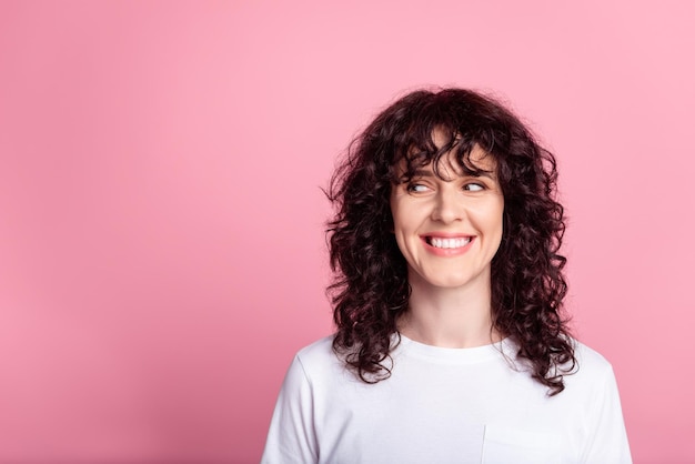 Foto de uma jovem alegre, imaginando: olhar um espaço vazio inteligente isolado sobre um fundo de cor rosa