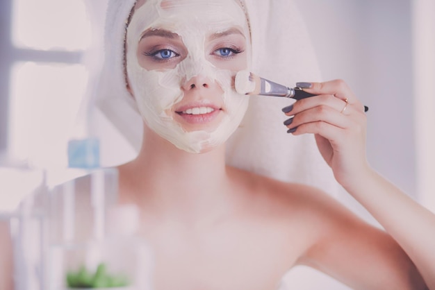 Foto de uma jovem aplicando pó facial no banheiro