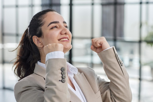 Foto de uma jovem assistente de escritório muito feliz levantando os punhos