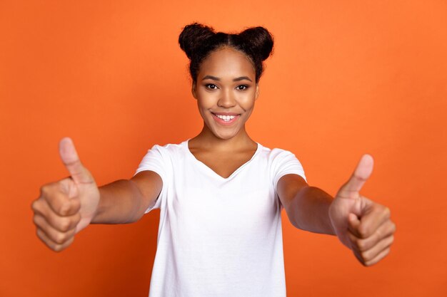 Foto de uma jovem bonita mostra publicidade de polegar para cima aprova grande isolado sobre fundo de cor laranja