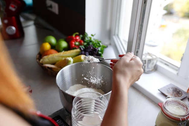 Foto de uma jovem bonita parada na cozinha enquanto cozinha peixe olhando de lado Preparação de torta de limão