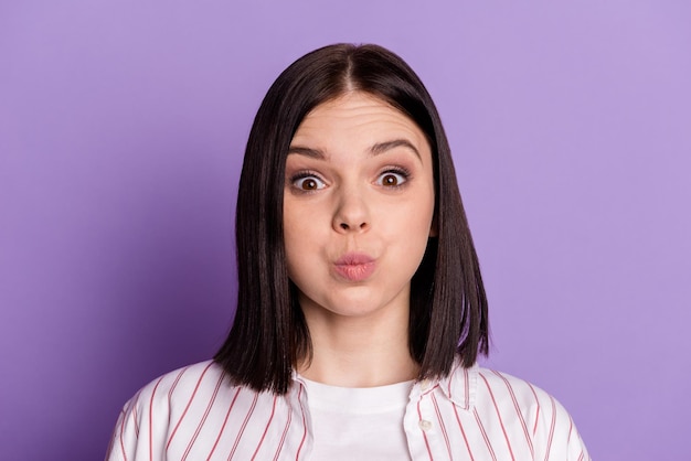 Foto de uma jovem com bochechas amuadas enganando a careta de piada de respiração isolada sobre fundo de cor violeta