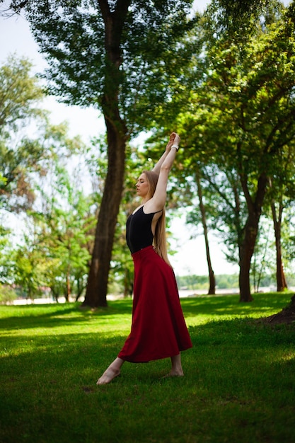 foto de uma jovem dançarina do ventre em um parque uma jovem loira dançando na natureza ginasta