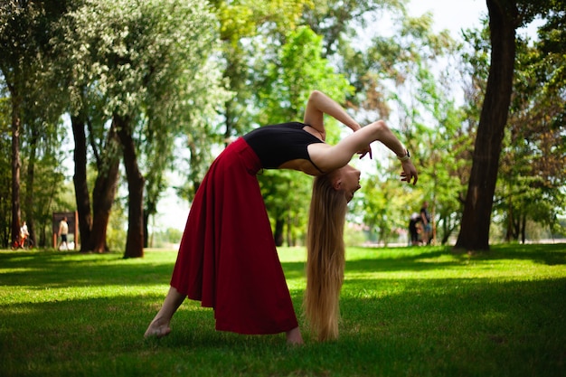 foto de uma jovem dançarina do ventre em um parque uma jovem loira dançando na natureza ginasta