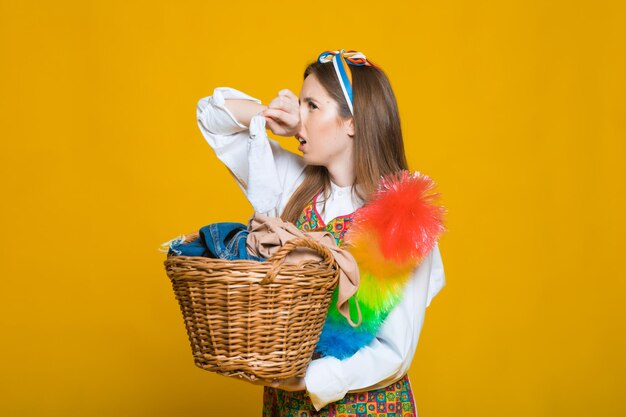 Foto de uma jovem dona de casa infeliz de 20 anos carregando cesto de roupa suja com roupas sujas isoladas