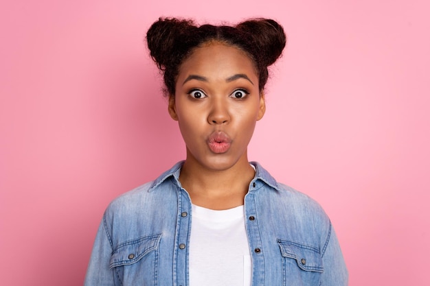 Foto de uma jovem e adorável africana com lábios amuados envia beijo de ar romântico isolado sobre fundo cor-de-rosa