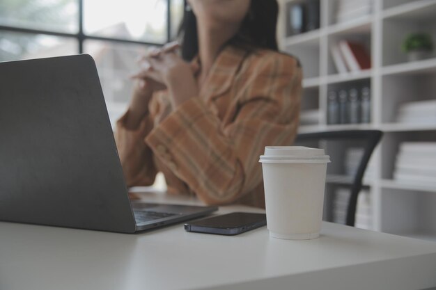 Foto de uma jovem empresa asiática trabalhando em um laptop em sua estação de trabalho