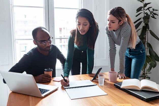 Foto de uma jovem empresária explicando um projeto para seus colegas no local de coworking.