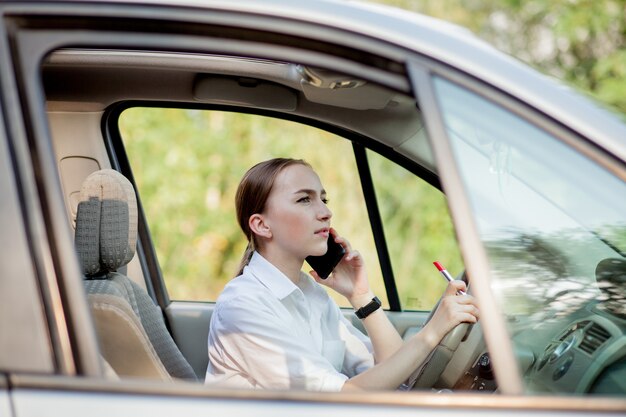 Foto de uma jovem empresária falando ao telefone e fazendo maquiagem