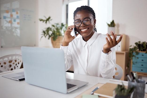 Foto de uma jovem empresária usando um laptop e smartphone em um escritório moderno