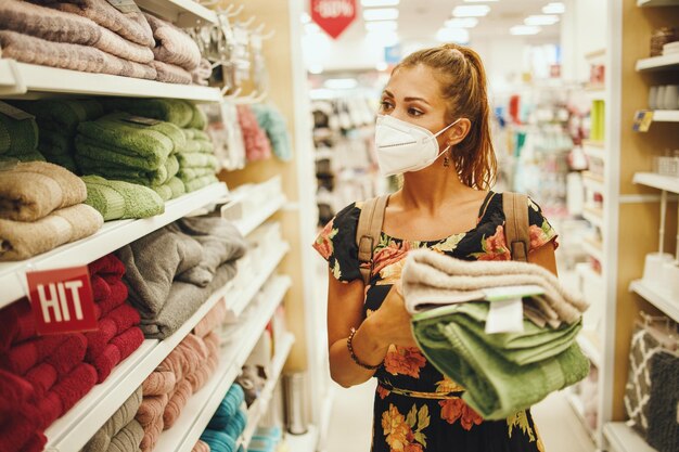 Foto de uma jovem está usando máscara protetora N95 enquanto compra toalhas no supermercado durante a pandemia de Covid-19.