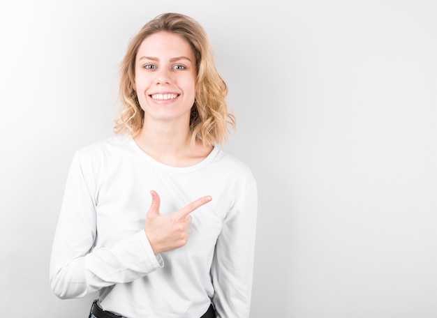 Foto de uma jovem feliz em pé, isolada sobre uma parede branca