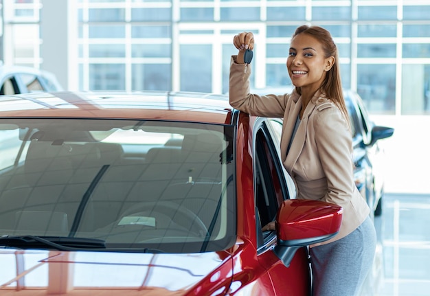 Foto de uma jovem feliz mostrando a chave para seu novo conceito de carro para aluguel de carros