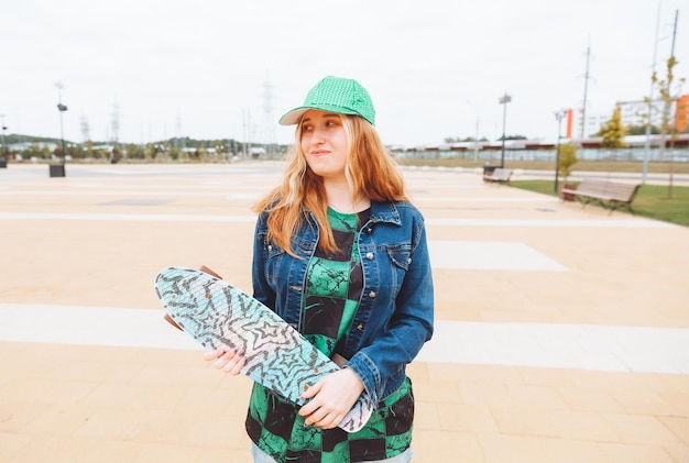 Foto de uma jovem linda caminhando ao ar livre com um adolescente de skate geração z