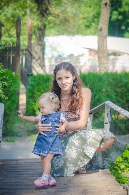 Foto de uma jovem mãe caminhando no parque com a filha pequena, brincando e sorrindo