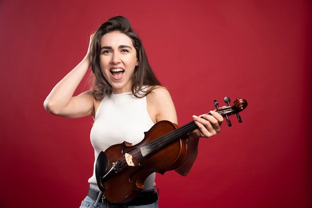 Foto de uma jovem modelo segurando um violino para aula de música
