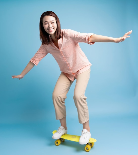 Foto de uma jovem mulher asiática patinando em fundo azul