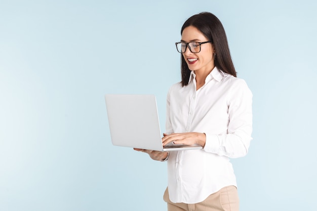 Foto de uma jovem mulher de negócios grávida isolada usando o computador portátil.