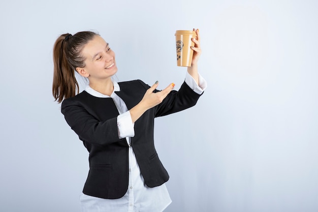 Foto de uma jovem mulher segurando uma xícara de café em branco.