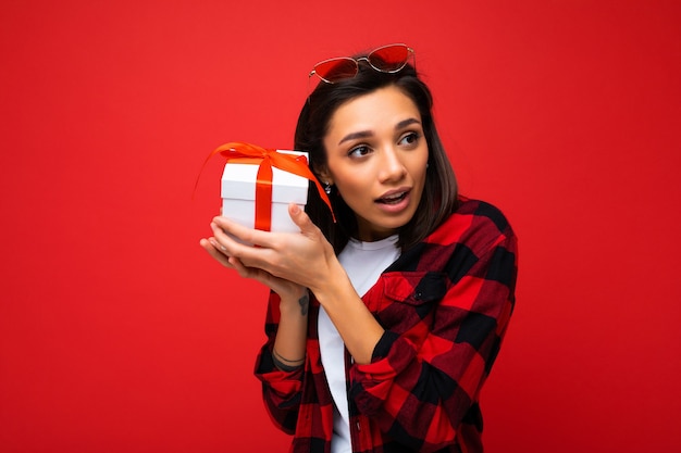 Foto de uma jovem pensativa e positiva isolada sobre uma parede de fundo vermelho