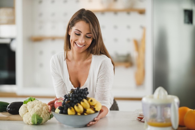 Foto de uma jovem preparando uma refeição saudável em sua cozinha.