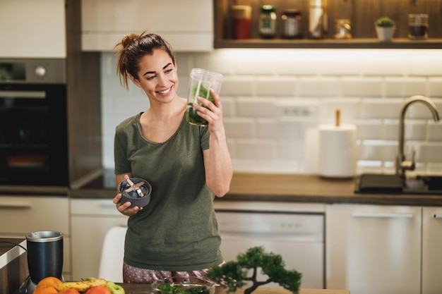 Foto de uma jovem sorridente fazendo um smoothie saudável na cozinha em casa.