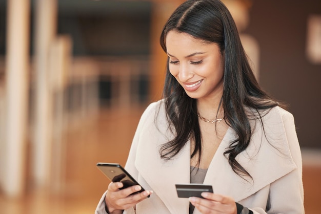 Foto de uma jovem usando seu smartphone para fazer um pagamento online usando seu cartão de crédito