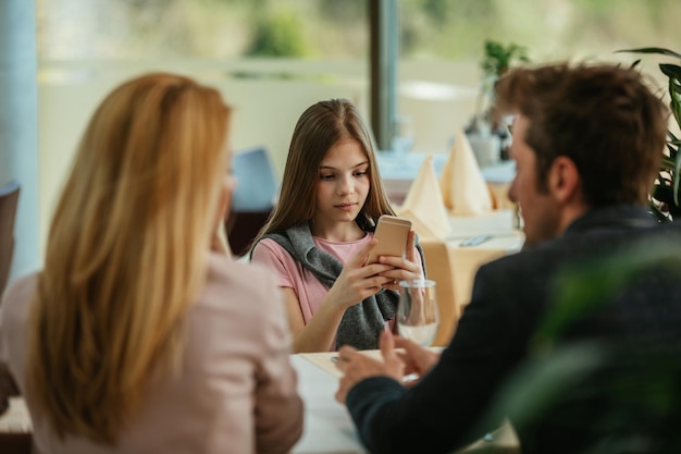 Foto de uma jovem usando um telefone celular em um restaurante