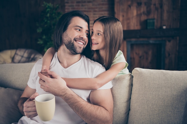 Foto de uma linda garotinha adorável e um jovem papai sentado no sofá confortável