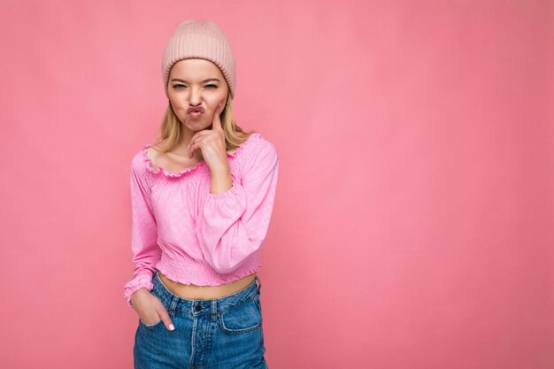 Foto de uma linda jovem loira engraçada feliz isolada sobre uma parede de fundo rosa vestindo roupas da moda