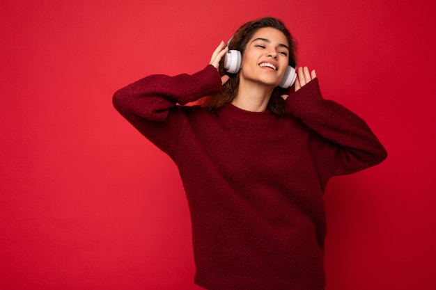 Foto de uma linda jovem morena encaracolada e sorridente, usando um suéter vermelho escuro isolado