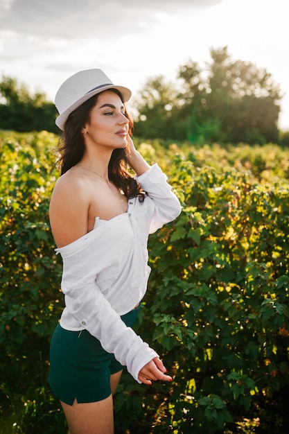 Foto de uma linda mulher morena no campo de camomila, fêmea fofa, apreciando o cheiro de margarida doce menina com os olhos fechados relaxados na natureza primavera prado de flores se divertindo ao ar livre