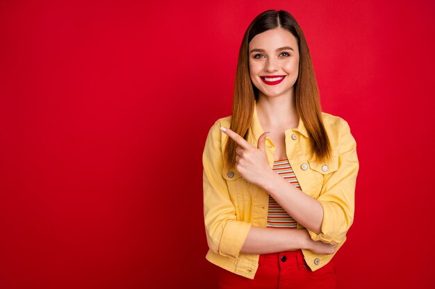 Foto de uma linda senhora bonita pomada brilhante bom humor lado do dedo direto espaço vazio aconselhando novidade produto usar jaqueta jeans casual amarela blazer isolado fundo de cor vermelha viva