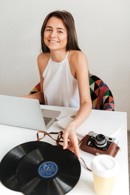 Foto foto de uma linda senhora casual trabalhando em um laptop sentado na cadeira da casa, mantendo o registro.